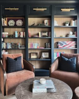Finally got some shots of this custom library wall, one of my favorite projects to date. Painted in a rich, inky blue to match the walls and ceiling for a seamless, built-in feel. The goal was for it to feel like it’s always been there and I think we nailed it.

We added reeded wood paneling to the back to give the shelving depth and texture, finishing it with brass picture lights for that classic library vibe.

The furnishings were kept warm and simple to let the millwork shine. Cognac velvet chairs, a marble coffee table, soft wool rug, and subtle patterned ottomans.

A room made for slow evenings and good books✨📚